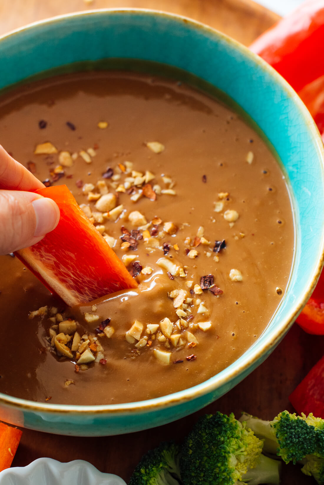 dipping slice of bell pepper into peanut sauce