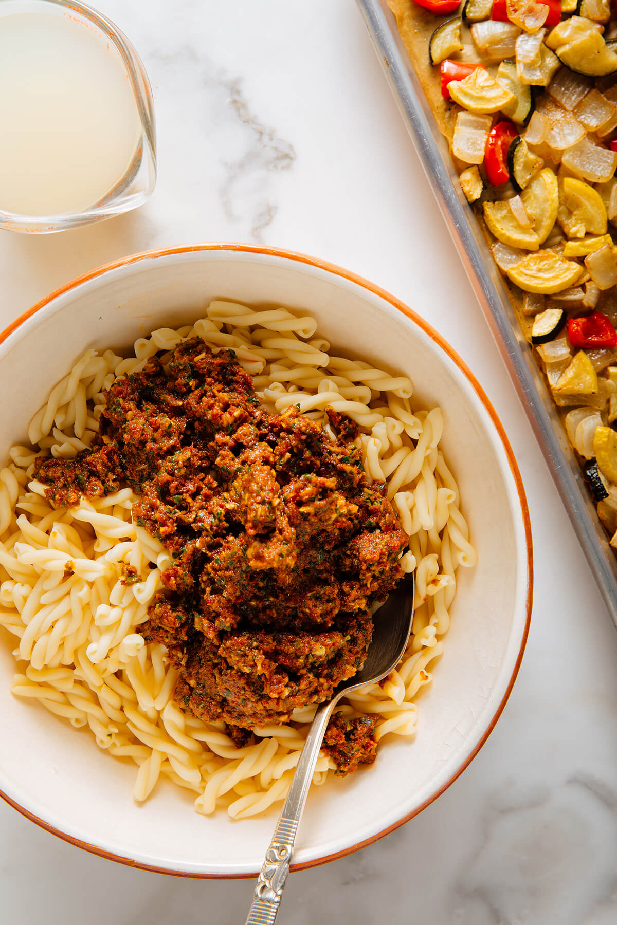 stirring red pesto into pasta
